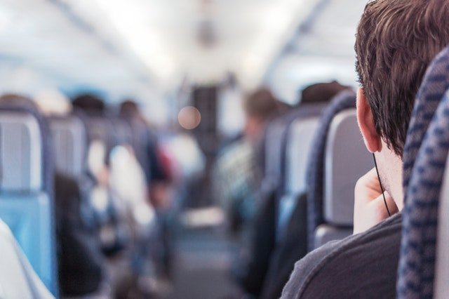 Chlap sediaci v lietadle so slúchadlami na ušiach